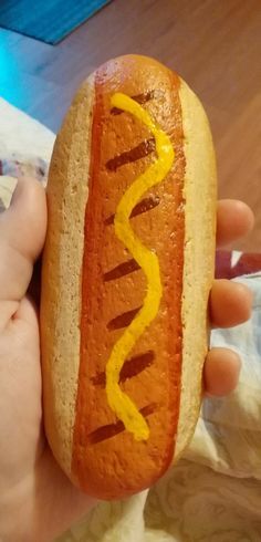 a hand holding a hot dog with mustard on it