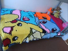 there is a crocheted blanket that looks like pokemons on the bed with stuffed animals next to it