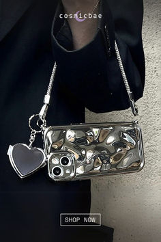 a woman is holding a silver purse with hearts on the front and side, while wearing a black jacket