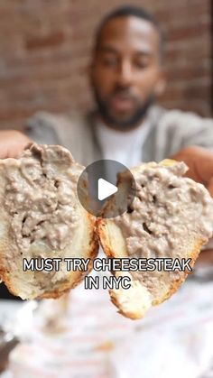 a man holding up a sandwich with meat on it in front of him and the words must try cheesesteak in ny