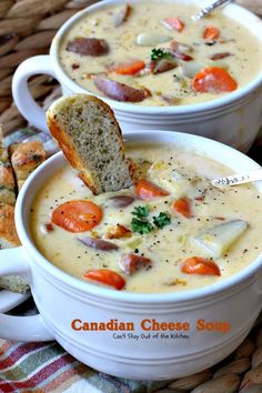 two bowls of canadian cheese soup on a table with bread and carrots next to it