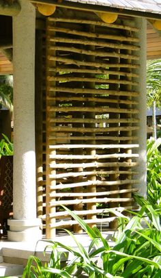 a house with wooden slats on the front and side of it, surrounded by greenery