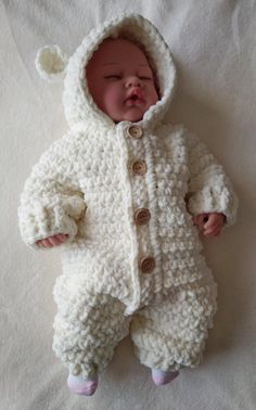 a baby is wearing a white crochet outfit and sleeping on the bed with its eyes closed