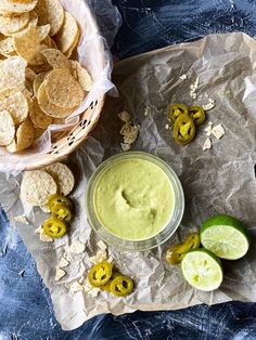 a bowl of guacamole next to some chips and limes