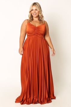 a woman in an orange dress poses for the camera with her hands on her hips