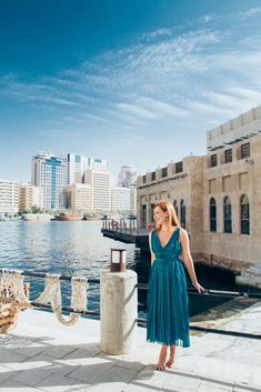 a woman in a blue dress standing on the edge of a pier