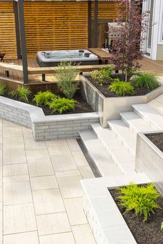 an outdoor hot tub surrounded by plants and landscaping area with steps leading up to it