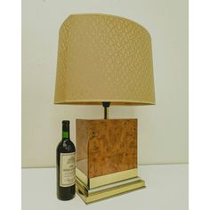 a bottle of wine sitting next to a lamp on a table with a cork base