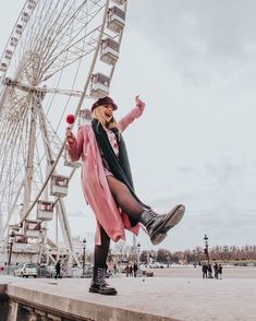 a woman standing on the edge of a pier next to a ferris wheel