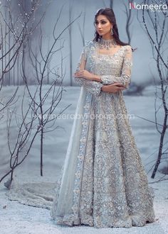 a woman standing in front of some trees wearing a silver gown and matching with a white shawl