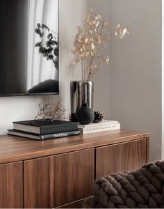 a vase with flowers on top of a wooden dresser next to a book and other items