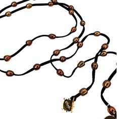 This pearl lariat necklace is made with cinnamon colored freshwater pearls. The brownish color on the black leather is a stunning contrast against black. It wold be nice with animal prints that have black and browns. At 50" long there are many ways to tie it. A linked video shows how to do this but you will see the white pearls in the video. Last phots shows how it looks wrapped multiple times on your wrist as a bracelet. You tie and leave the ends to dangle as a tassel. Elegant Brown Necklace With Adjustable Cord, Adjustable Brown Lariat Necklace, Brown Adjustable Lariat Necklace, Adjustable Brown Long Lariat Necklace, Adjustable Brown Hand Knotted Necklaces, Elegant Brown Necklace With Adjustable Length, Brown Adjustable Hand Knotted Necklace, Handmade Brown Lariat Necklace, Adjustable Beaded Brown Lariat Necklace