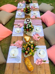 a table set up with flowers, bread and plates on it for an outdoor meal