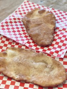 two pieces of fried food sitting on top of red and white checkered napkins