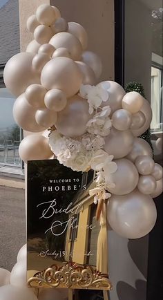 a bunch of balloons that are in front of a sign and some flowers on a chair