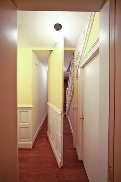 an empty hallway with yellow walls and white trim on the door, leading to another room