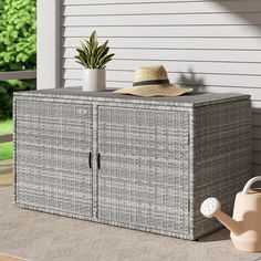 a gray wicker cabinet with a hat and watering can on the ground next to it