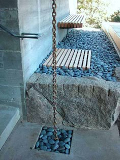 a bench sitting on top of a cement slab next to a stone wall and water feature