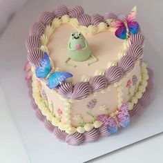 a heart shaped cake decorated with butterflies and fondant icing on a white surface