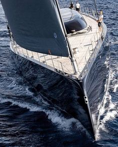 a large boat sailing across the ocean with people on it's deck and in the water