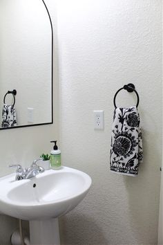 a white sink sitting under a mirror next to a wall mounted faucet and soap dispenser