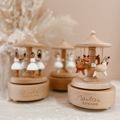 three wooden carousels sitting on top of a white table next to a vase with flowers