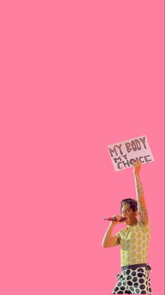 a man holding up a sign that says my body is change on it in front of a pink background