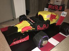 a car made out of paper sitting on top of a black mat next to a red bull sign