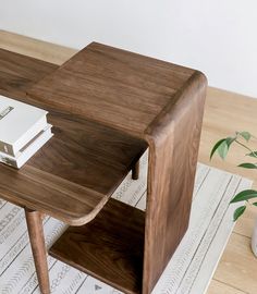 a wooden table with a book on it and a plant in the corner next to it