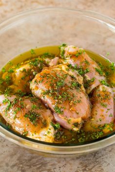 a glass bowl filled with chicken covered in sauce and garnished with parsley