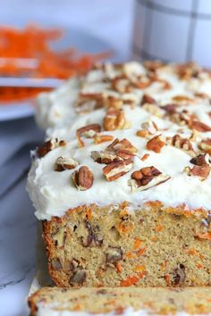 carrot cake with cream cheese frosting and pecans on top, ready to be eaten