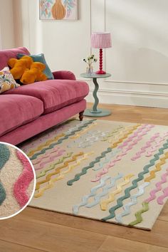 a living room with a pink couch and colorful rugs on the wooden flooring