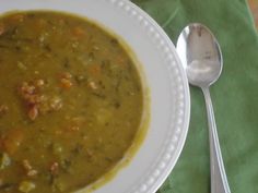 a white bowl filled with soup next to a spoon on top of a green napkin