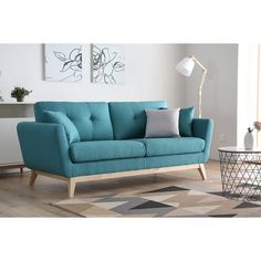 a blue couch sitting on top of a hard wood floor next to a white wall