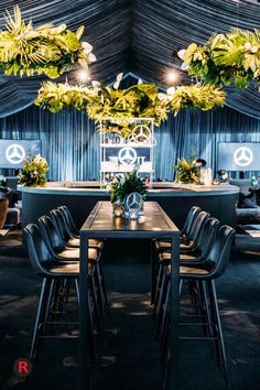 a dining room with chairs and tables surrounded by greenery hanging from the ceiling above