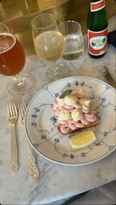 a plate with food on it next to two glasses of wine and a bottle of beer