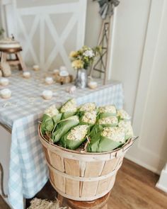 a basket filled with flowers sitting on top of a table next to a blue and white checkered table cloth