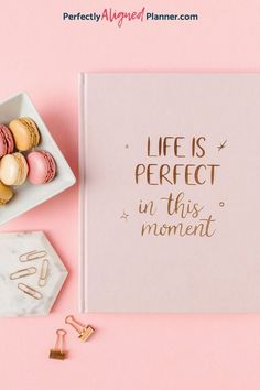 a notebook with the words life is perfect in this moment next to some macaroons