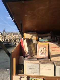 many books are stacked on top of each other in the back of a boat with a bridge in the background