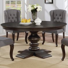 a dining room table with grey chairs and a bowl of fruit on the top of it