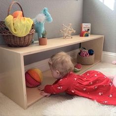 a toddler playing with toys on the floor in front of a bookshelf