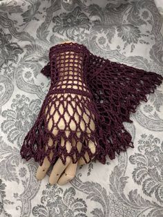 a pair of gloves with crochet on top of a tablecloth covered in fabric