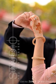 a woman in a pink dress is holding her arm up to the side with two bracelets on it