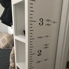 a tall white book shelf with a ruler on it's front and back sides