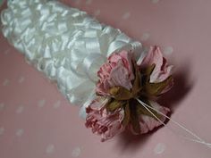 a pink and white flower is on top of a wedding garter, which is attached to a string