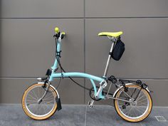 a blue and yellow bicycle parked next to a gray wall