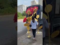 the woman is walking down the street with flowers in her hand, and she has on a white shirt