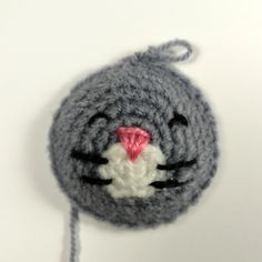 a crocheted gray and white cat with pink nose on it's head