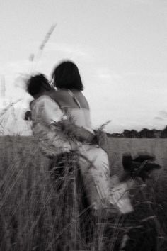 black and white photograph of two people sitting in tall grass