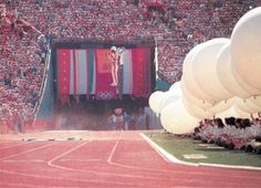 an olympic event with balloons in the air and people sitting on the sidelines watching